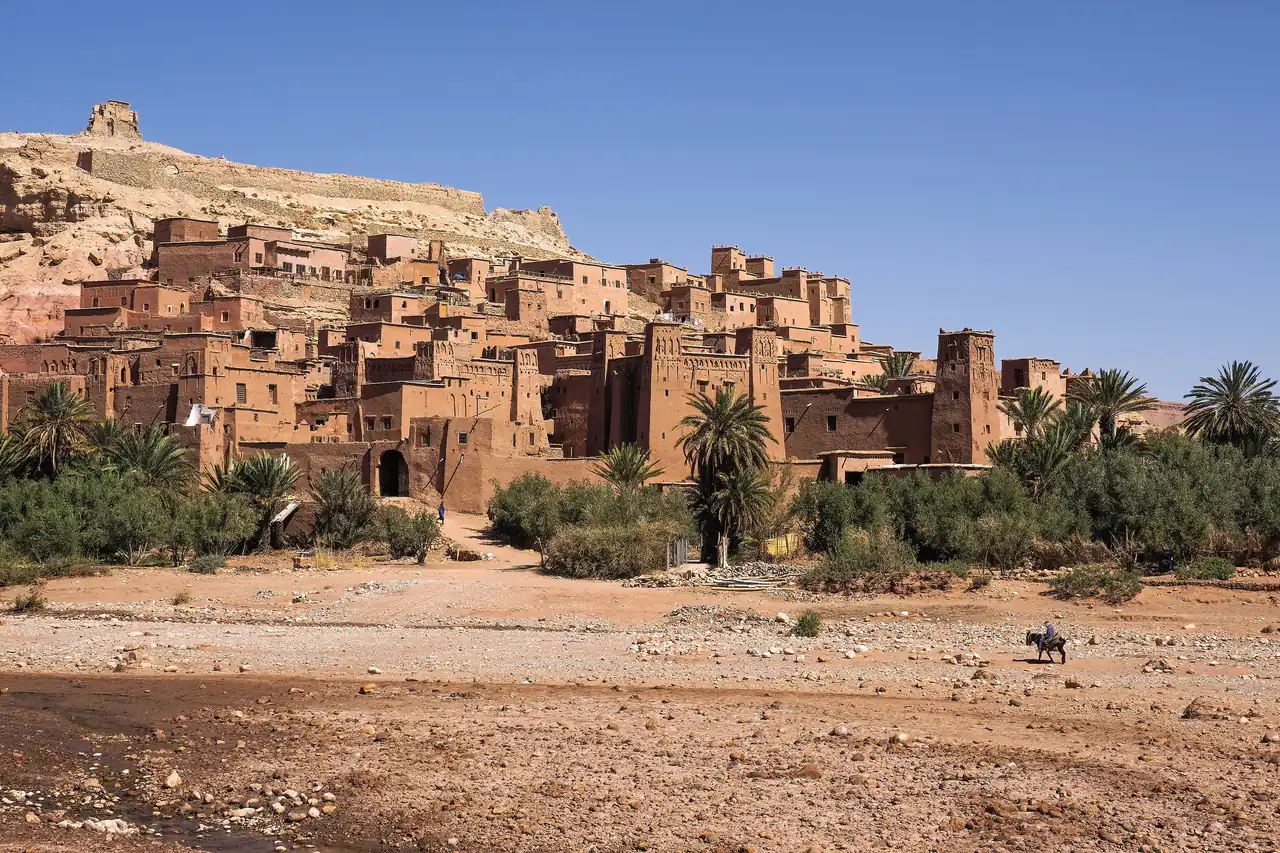 Earthen ksar of Ait Benhaddou rising above the riverbed and palms
