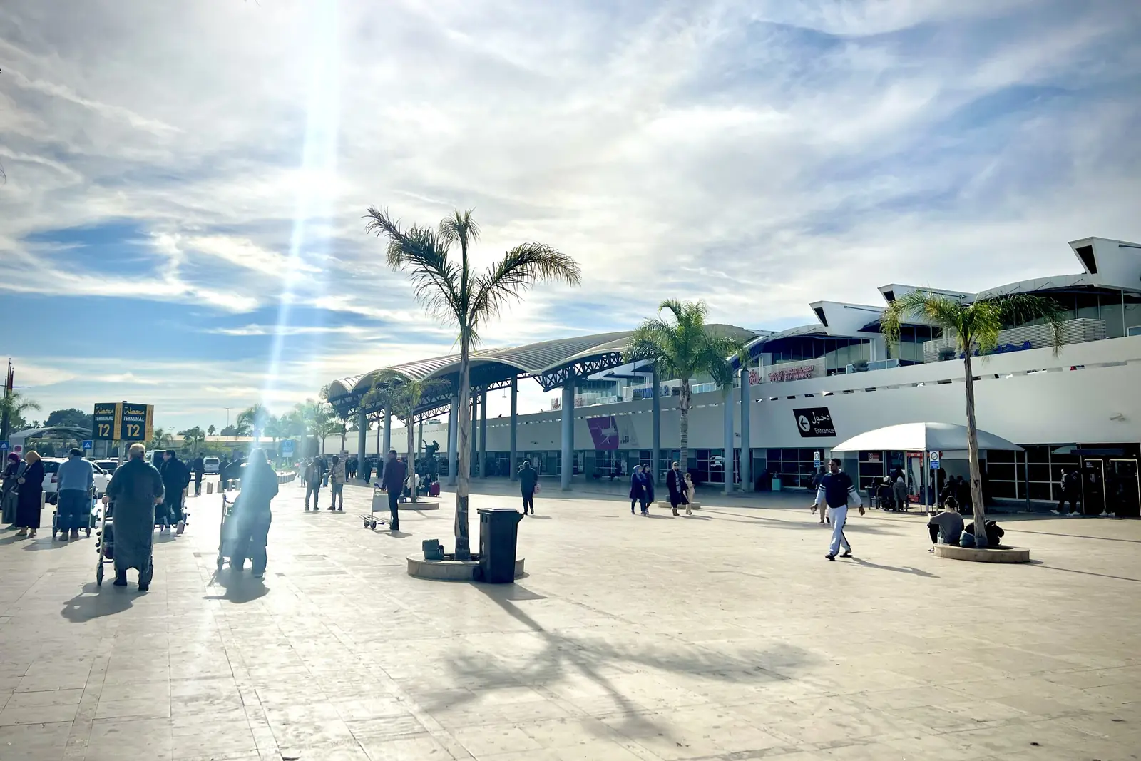 Travellers with luggage on the forecourt outside the Mohammed V Airport terminal in Casablanca