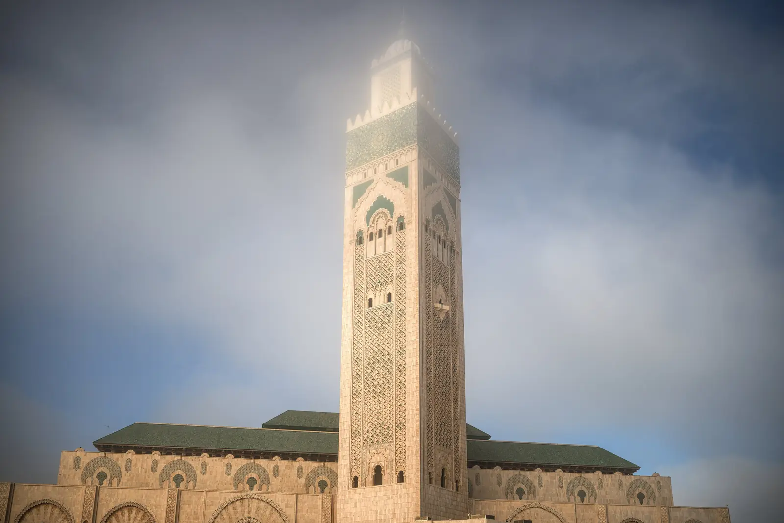 Minaret and front facade of the Hassan II Mosque in Casablanca, with sea mist around the top of the minaret