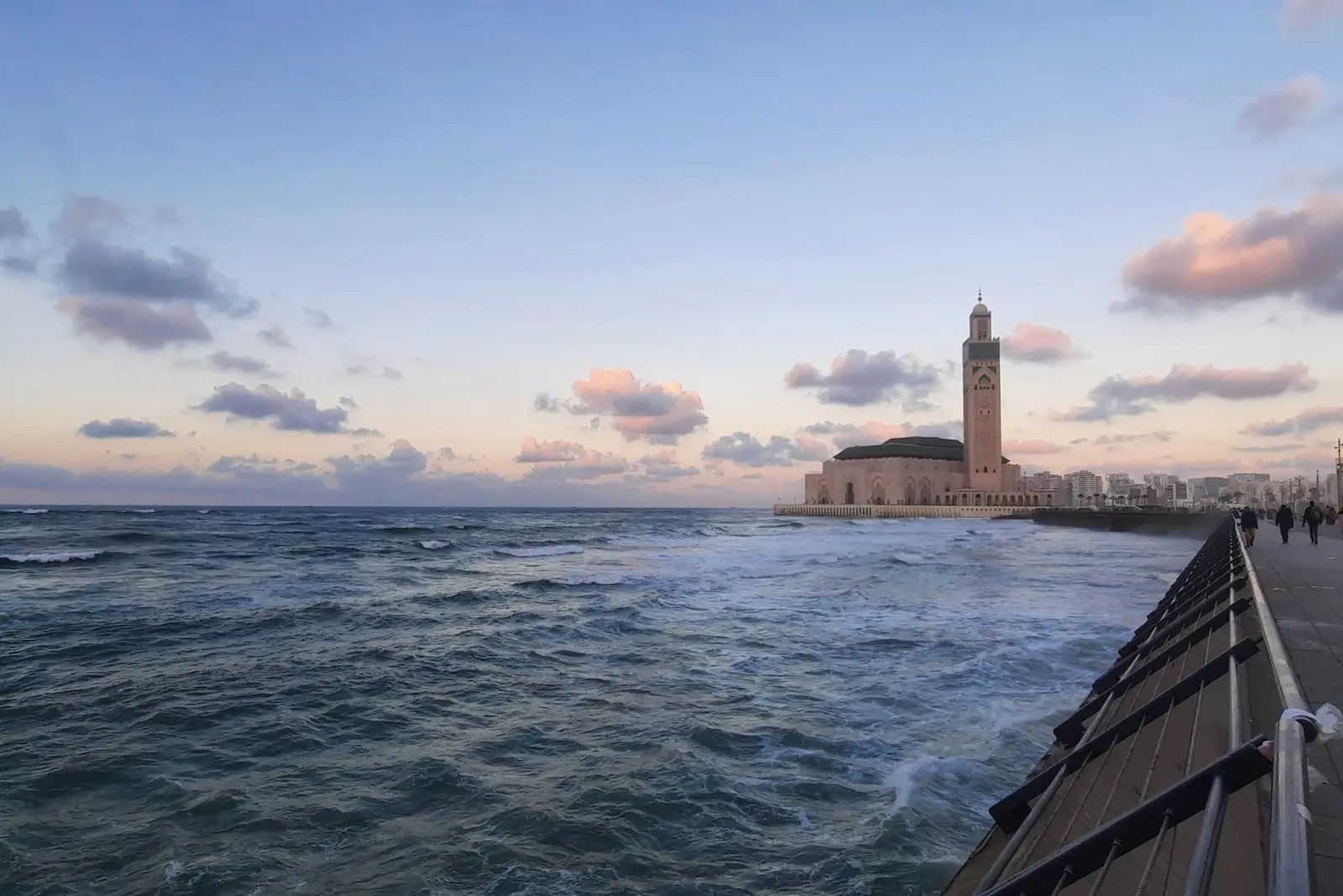 Hassan II Mosque on the Atlantic shore, seen from the Casablanca corniche walkway with waves in the foreground